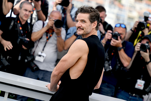 Pedro Pascal poses looking over his shoulder in a black sleeveless T-shirt at the Cannes Eddington Photocall