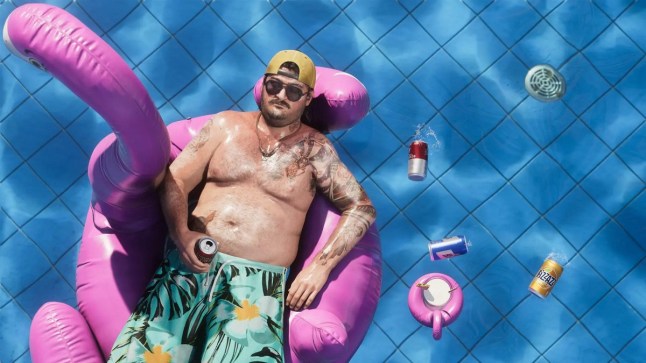 GTA 6 Cal lounging in a flamingo floatie in a swimming pool whole beer cans float next to him