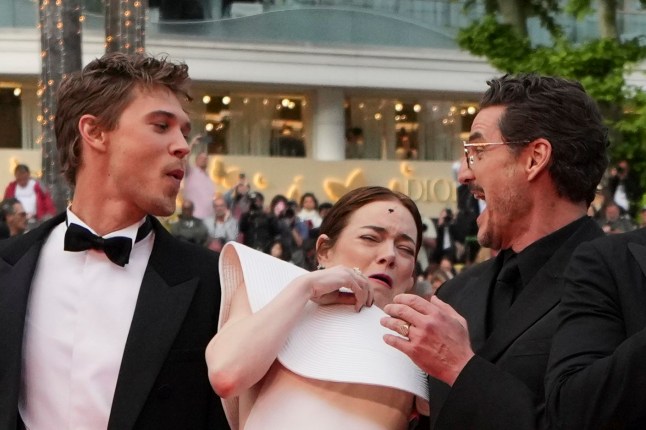 Emma Stone, centre, avoids a bee while posing with Austin Butler, left, and Pedro Pascal upon arrival at the premiere of the film 'Eddington' at the 78th international film festival, Cannes, southern France, Friday, May 16, 2025. (AP Photo/Natacha Pisarenko)